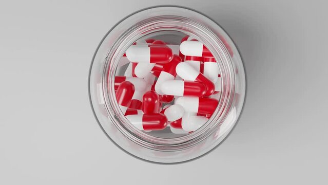 frasco transparente lleno de capsulas y medicinas en un fondo blanco, vista frontal y cenital 