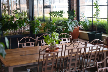 Fototapeta na wymiar Restaurant with wooden and metal furniture, big windows and plants