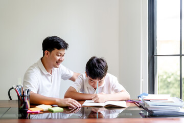 Father helping his son doing homework and studying education at home with happiness family moment