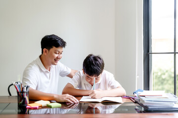 Fototapeta premium Father helping his son doing homework and studying education at home with happiness family moment
