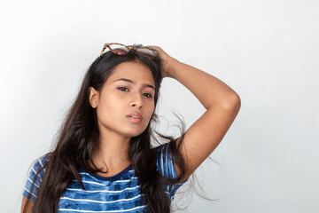 Studio shot of a young, beautiful Indian female model in casual wear, wearing blue and white printed top and a clear eyeglass against white background. Advertisement shoot. Eyeware product shoot.