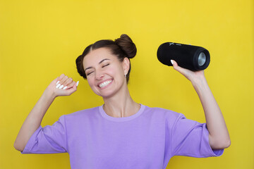 a young pretty Caucasian woman in a purple T-shirt listens to music and dances, closing her eyes,...