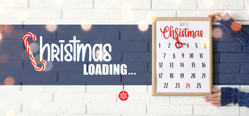 Female hands with Christmas advent calendar and text CHRISTMAS LOADING on white brick background