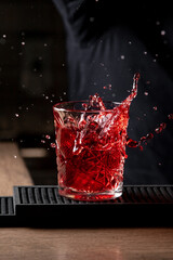 Negroni cocktail with ice, splashes from falling ice