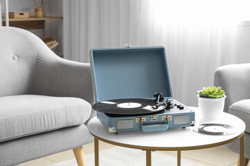 Record player with vinyl disk on table in living room