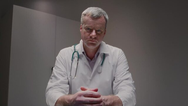 Male medic in work uniform displays shadowy X-ray to patient elucidating harm depicted in image in hospital equipped with machinery. Consultation with expert in healthcare facility slow motion