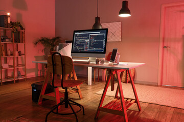Programmer's workplace with devices in interior of dark office