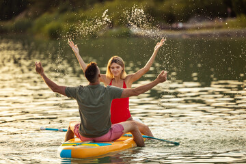 Paddle sup board surfers woman and man on sunset.