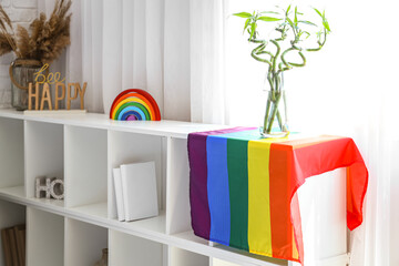 Vase with bamboo stems and LGBT flag on shelf in bedroom