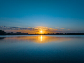 Sunrise waterscape with a scattering of clouds and reflections