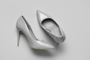 Stylish grey high heels on color background