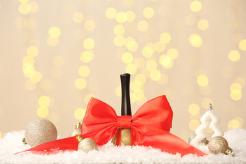 Christmas bell with red bow and balls on table against blurred lights