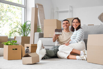 Happy young couple with house model in room on moving day