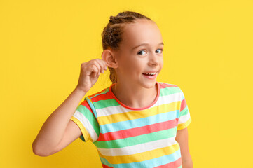 Little girl with hearing problem on yellow background