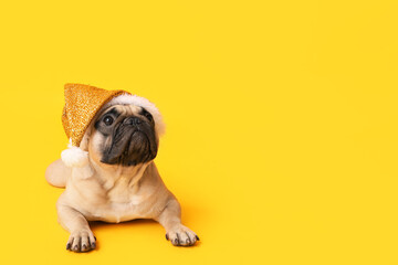 Cute pug dog in Santa hat lying on yellow background - Powered by Adobe