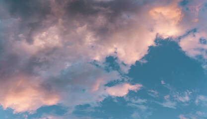 Scenic rose golden glowing big cloud highlighted by Sunset. Close up panoramic aerial photo of deep blue sky with puffy clouds