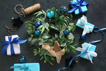 Christmas mistletoe wreath with balls and gift boxes on dark background