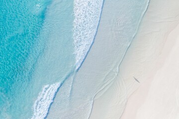 Aerial image captures a man on a sun-kissed beach and the calm blue waters of the sea