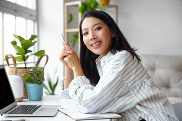 Young Asian woman working with laptop at home office