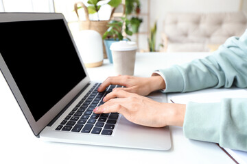 Young woman working with laptop at home office, closeup