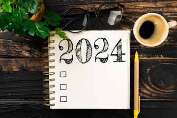 New year resolutions 2024 on desk. 2024 resolutions list with notebook, coffee cup on wooden table....