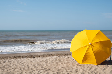 Yellow beach umbrella on the beach with the sea background
