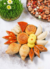 Traditional Azerbaijan holiday Novruz background with green semeni,traditional azerbaijan sweets,shekerbura,qogal,paxlava,mutaki and different nuts and sweets,top view,space for copy