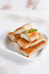 Crepes with cottage cheese, strawberry and mint. Thin pancakes with fillings
