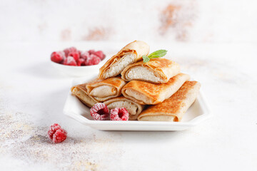 Crepes with cottage cheese, strawberry and mint. Thin pancakes with fillings