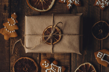 Fototapeta na wymiar Zero waste Christmas wrapping. Simple new year gift in craft paper on rustic wooden background with gingerbread cookies. Plastic free sustainable lifestyle flat lay top view