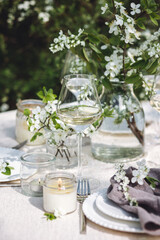 Romantic elegant luxury wedding table decor with white fresh spring blooming cherry apple tree flowers. Glass, candles, floral decoration for special marriage holiday event. No plastic zero waste
