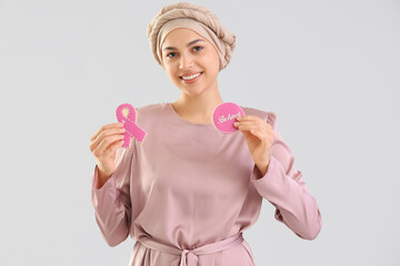 Young woman after chemotherapy with cookies on light background. Breast cancer awareness concept