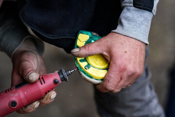 Man farrier installing plastic horseshoe to hoof. Closeup up detail to hands holding animal feet...