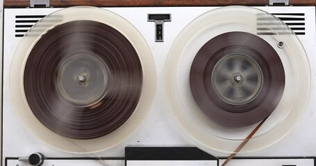 Old reel-to-reel tape recorder rewinds magnetic tape, vintage music player close-up
