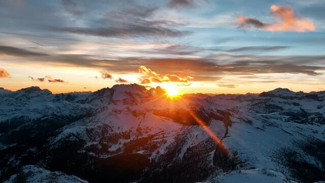 Tramonto sulle cime innevate delle alpi, riflessi del sole nelle nuvole fino alla sua scomparsa