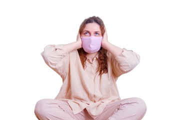 A woman in a medical mask holds on to her ears due to noise, isolated on a white background. Problems of remote work from home. The difficulty of working online at home