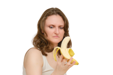 A woman with doubt and contempt looks at a banana, a studio, isolated on white background. A disgusted look at the banana fruit in the hands of a woman.
