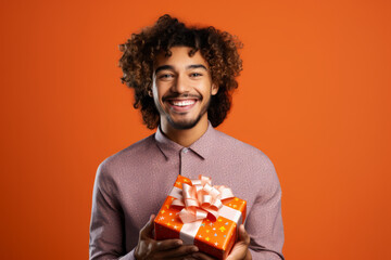 Happy smiling man holding gift box Medium shot portrait photography of a grinning mature man holding a gift against a tangerine orange background. - Powered by Adobe