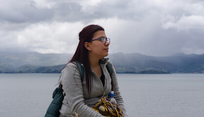 Latin woman with glasses serious looking at the horizon with a lake background