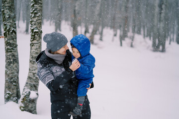 Fototapeta na wymiar Mom with a little girl in her arms stands in a snowy forest