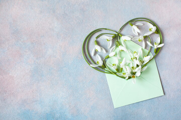 Envelope with snowdrop flowers in the shape of a heart, a beautiful card for the holidays in March, space for congratulation text - 670742798