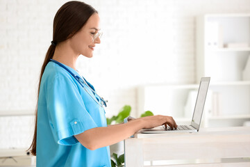 Female medical intern using laptop in clinic
