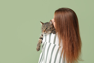 Woman with cute tabby cat on green background, back view
