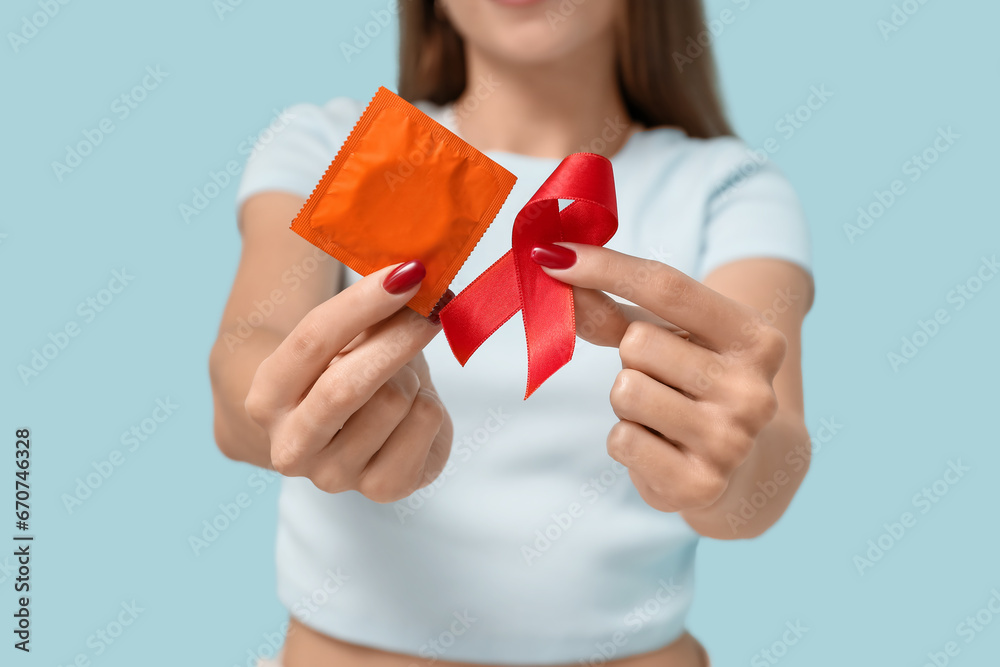 Sticker Woman with red ribbon and condom on blue background, closeup. World AIDS Day concept