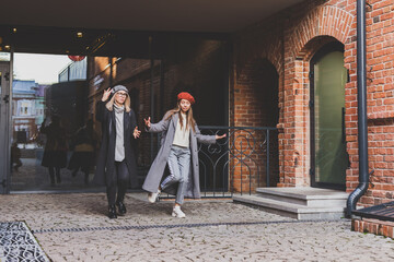 Naklejka premium Millennial young women having fun and dance on city street. Female funny friends enjoying autumn day around the city.