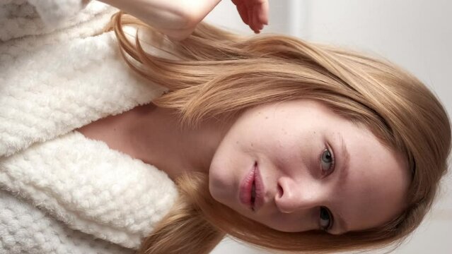 Vertical video. Natural beauty. Morning routine. Skincare wellness Satisfied confident blonde woman with clean radiant face skin in bathrobe.