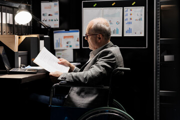 Professional accountant in wheelchair checking administrative paperwork in dark file room....