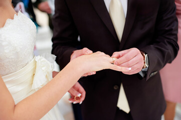 Love and marriage. Wedding ceremony. Close up of groom putting golden ring on the bride's finger.