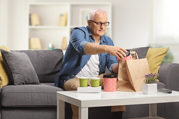 Mature man sitting on a sofa with takeaway delivery food