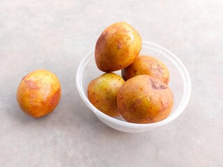 pile of ripe sapodilla fruit in a bowl on a gray background. fresh and healthy fruit.